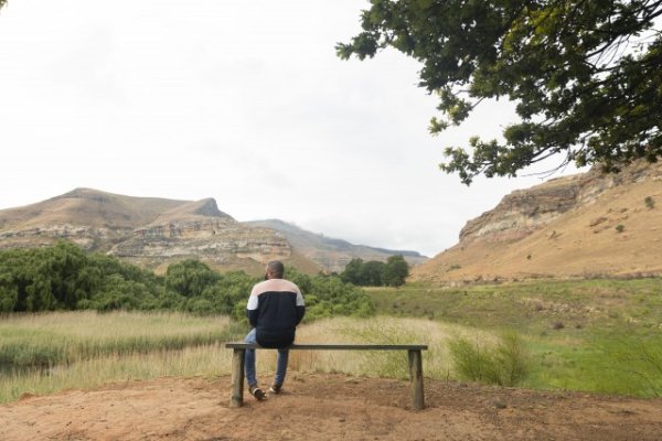 Black man sitting watching the mountains