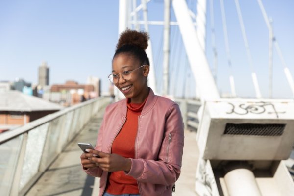 African woman smiling holding a smartphone