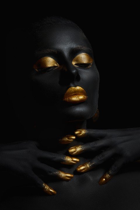 Beauty woman painted in black skin color body art, gold makeup l