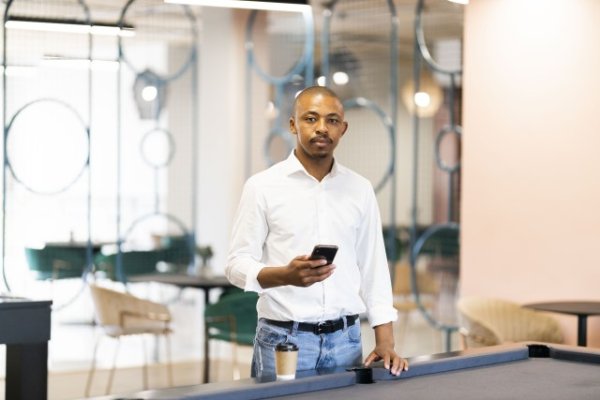 Black man on his cellphone by a pool table at work