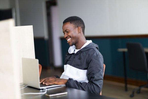 Black man celebrating looking at his laptop with a grin
