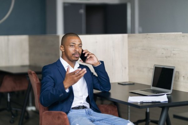 Black business man talking on his phone and wearing a suit at work