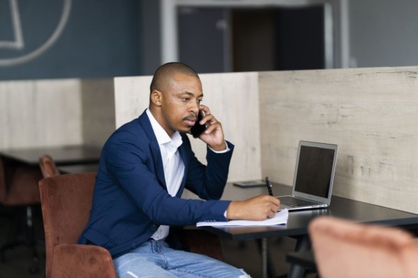 Black business man taking notes and on a phone call