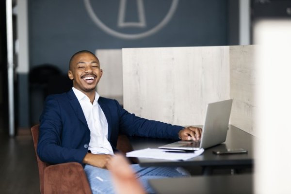 Black business man wearing a suit smiling at the camera at the office