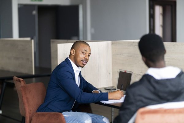 Black business man wearing a suit and talking to his client at work and taking notes
