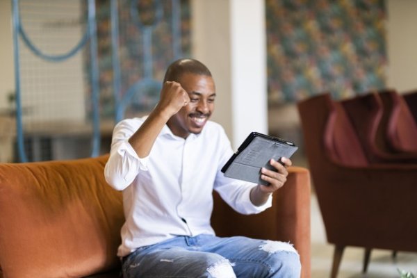 Black man celebrating and looking at ipad