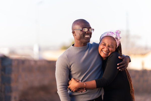 Black couple smiling outdoors with a blurred background of Alexandra.