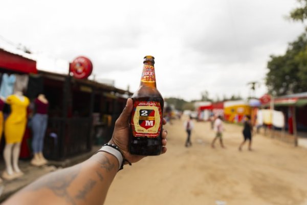 Black hand holding Mozambique beer in the air.