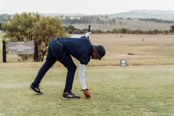 Black male golfer placing golf ball on the golf course