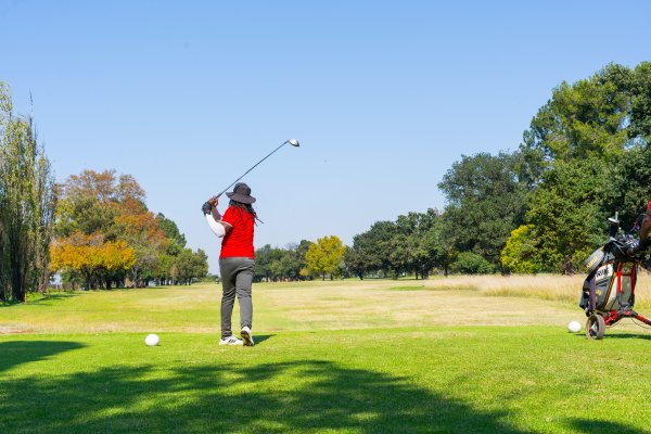 Black male golfer wearing a red golf shirt on the golf course driving