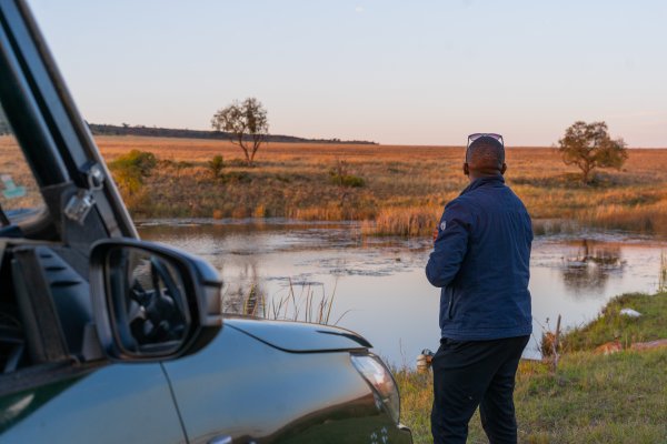 Black man at a dam near a car camping.