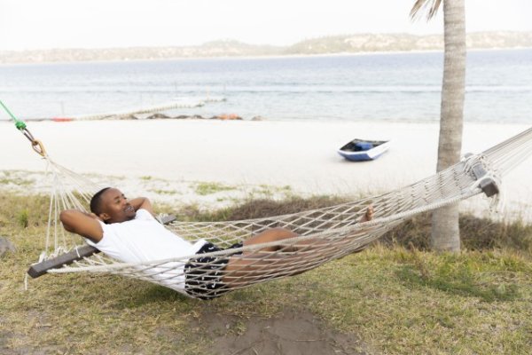 Black man laying on a hammock with a lagoon view.