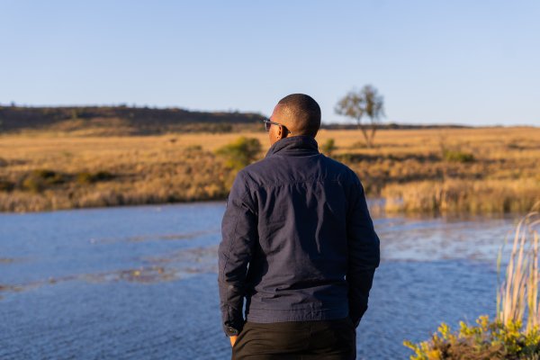 Black man overlooking a dam of water