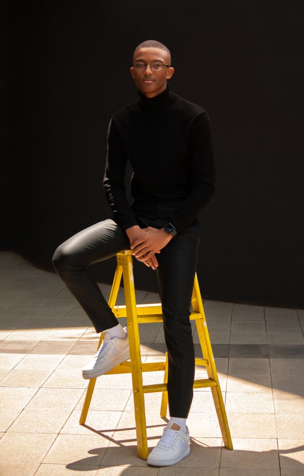 Black man sitting on a yellow ladder