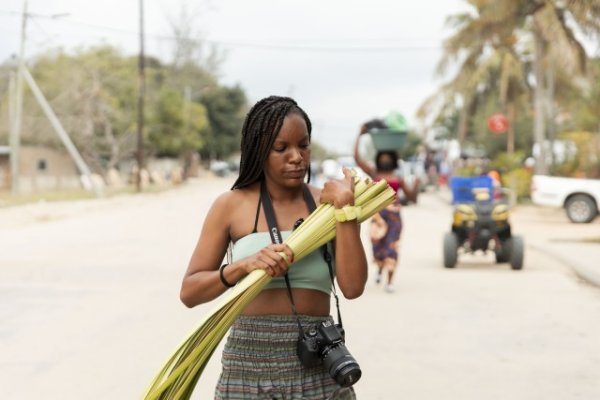 Black woman holding a camera and plants