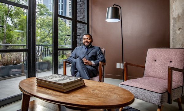 Corporate businessman sitting on a chair smiling with books on a table