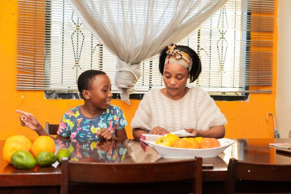 Family reading the bible at home, mom and son with fruits on the table.