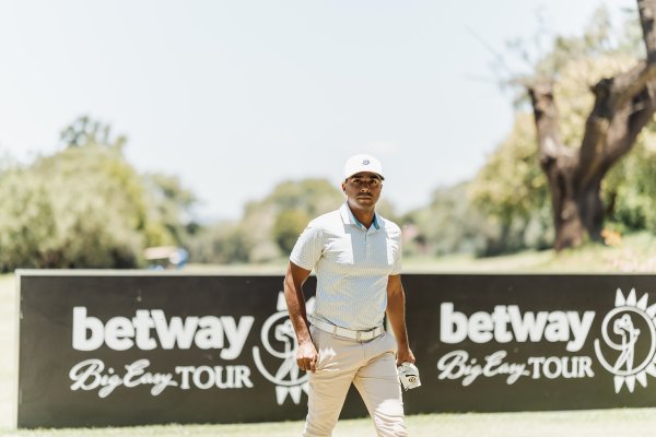 Golf player walking pass betray sign with glove in hand on a sunny day