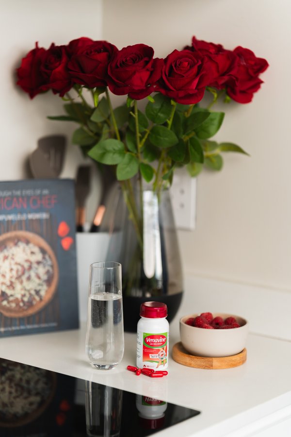 Health products on a marble table with flowers and food books behind.