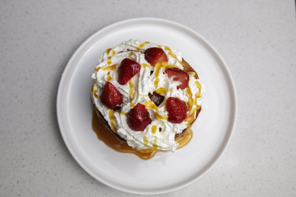 Flatlay of pancakes and cream on a plate with syrup.
