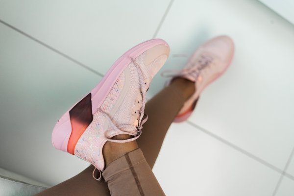 Pink running shoes worn by a black woman.