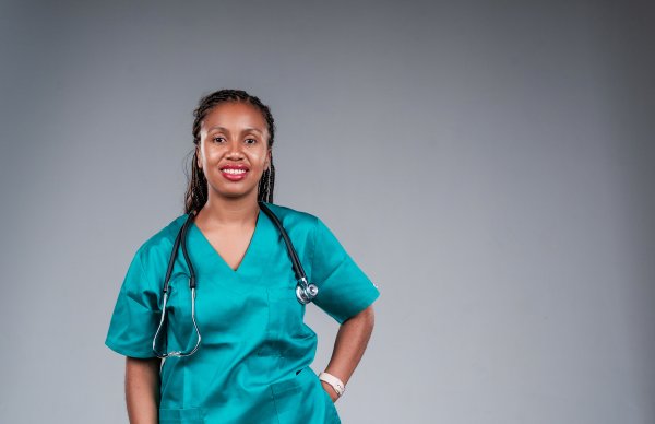 Portrait of happy medical doctor standing on grey background
