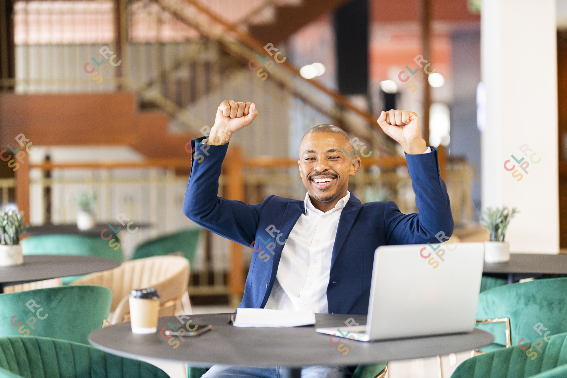 Black business man in a suit at work celebrating