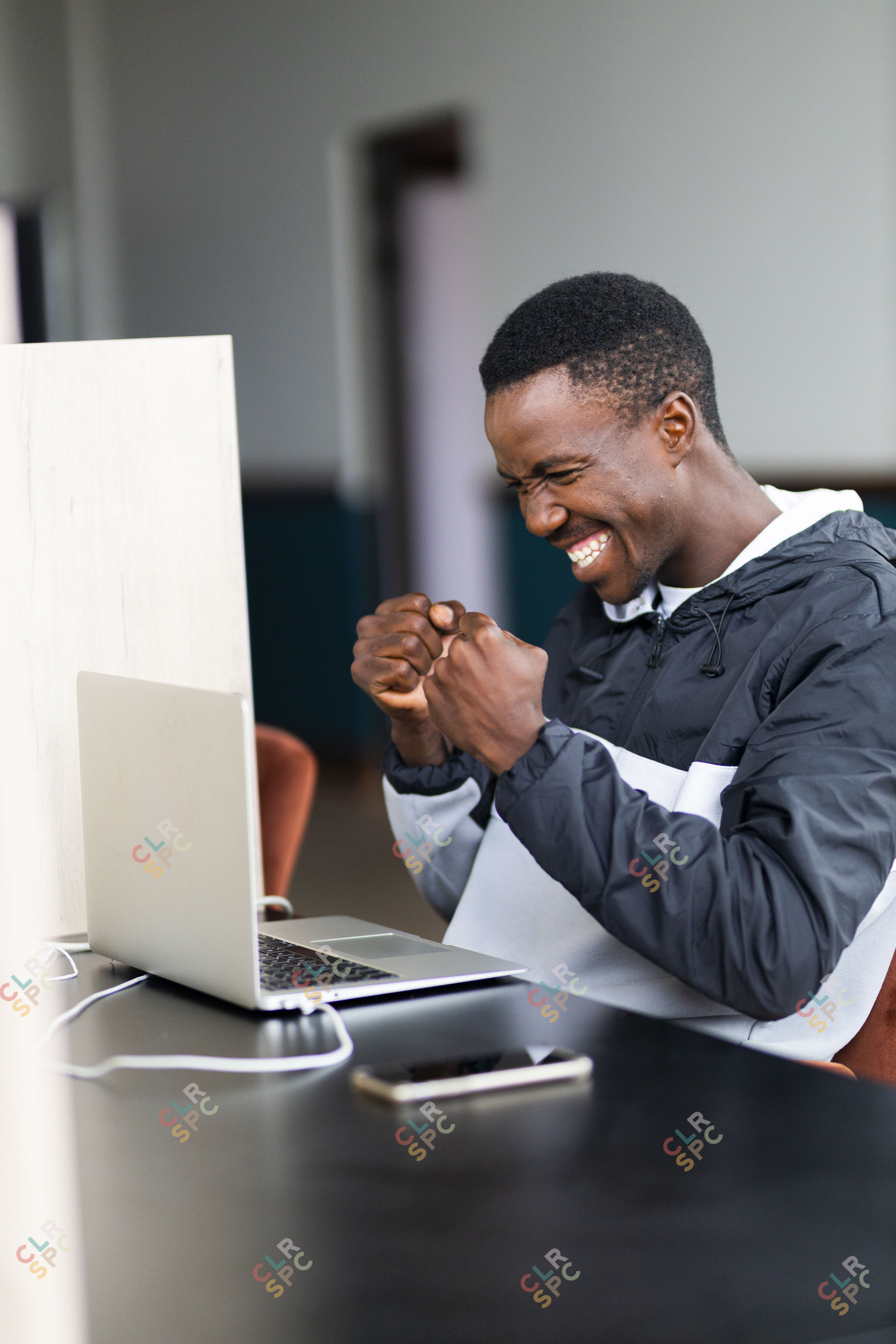 Black man celebrating a win and looking at his laptop with a grin