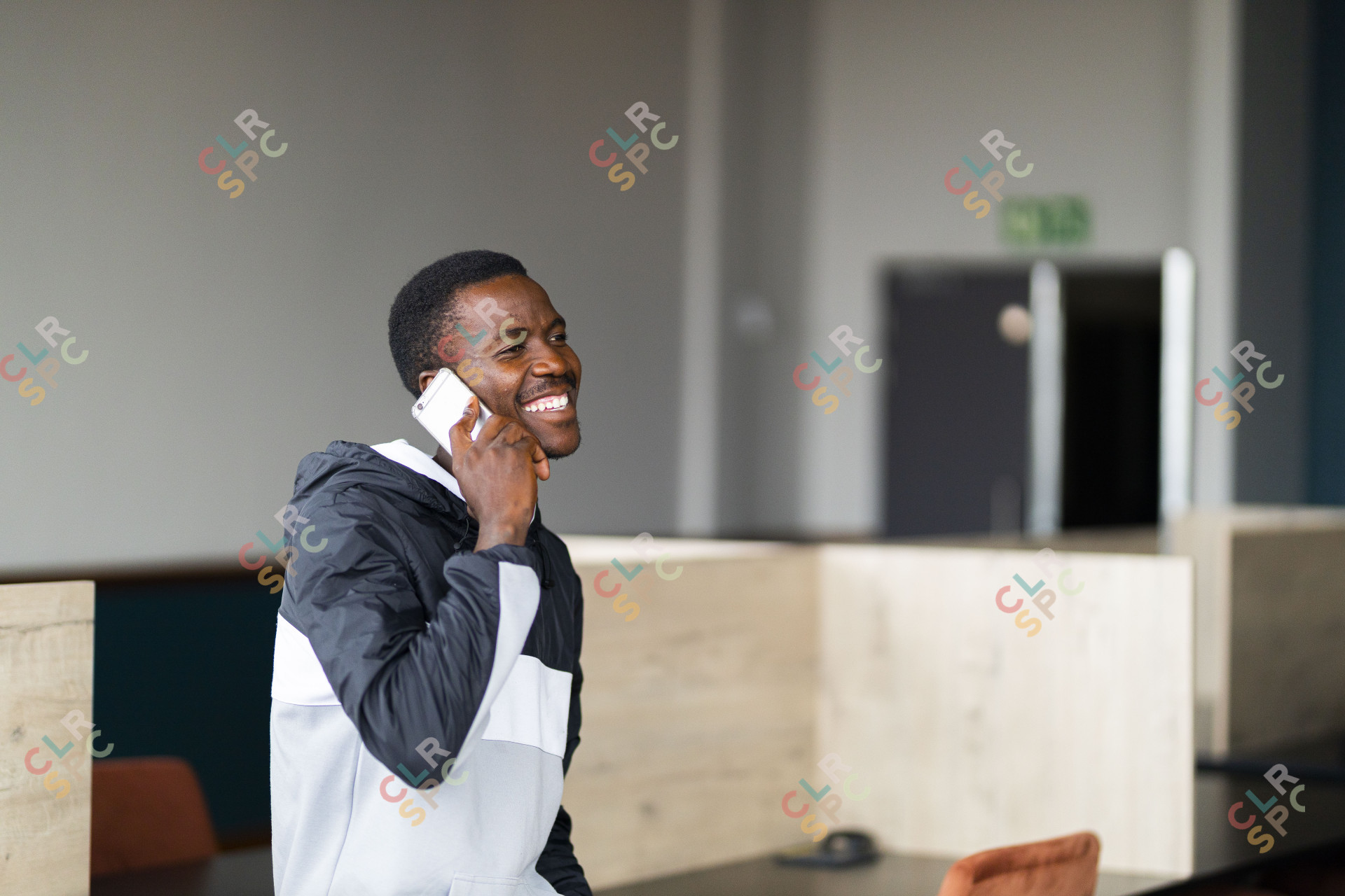 Black man talking on his cellphone at work and smiling