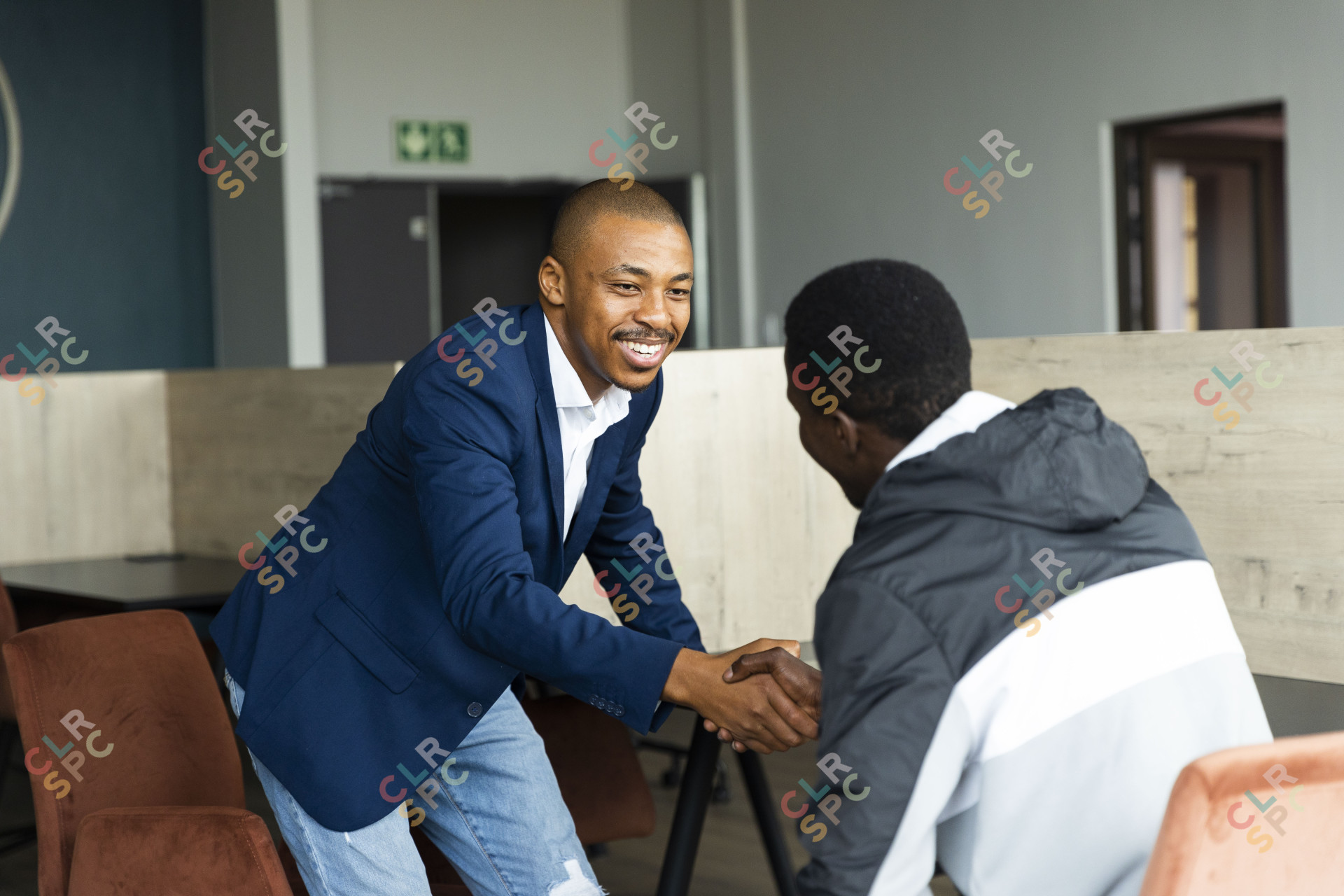 Black business man wearing a suit and shaking hands with a client at the office