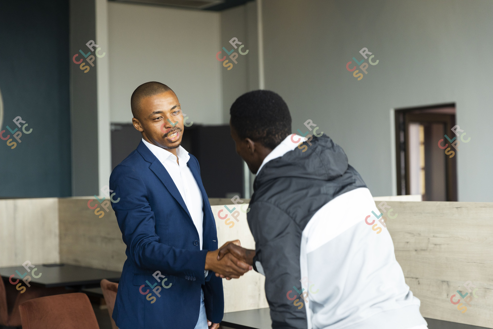 Black business man wearing a suit shaking hands with a client at the office