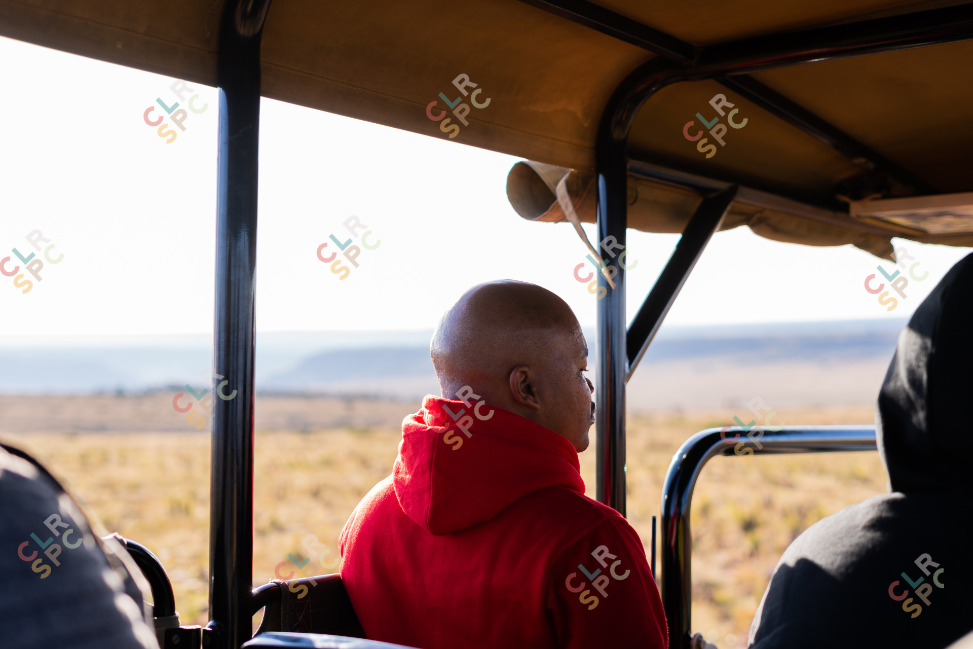 Black man in a safari car wearing a red jacket.