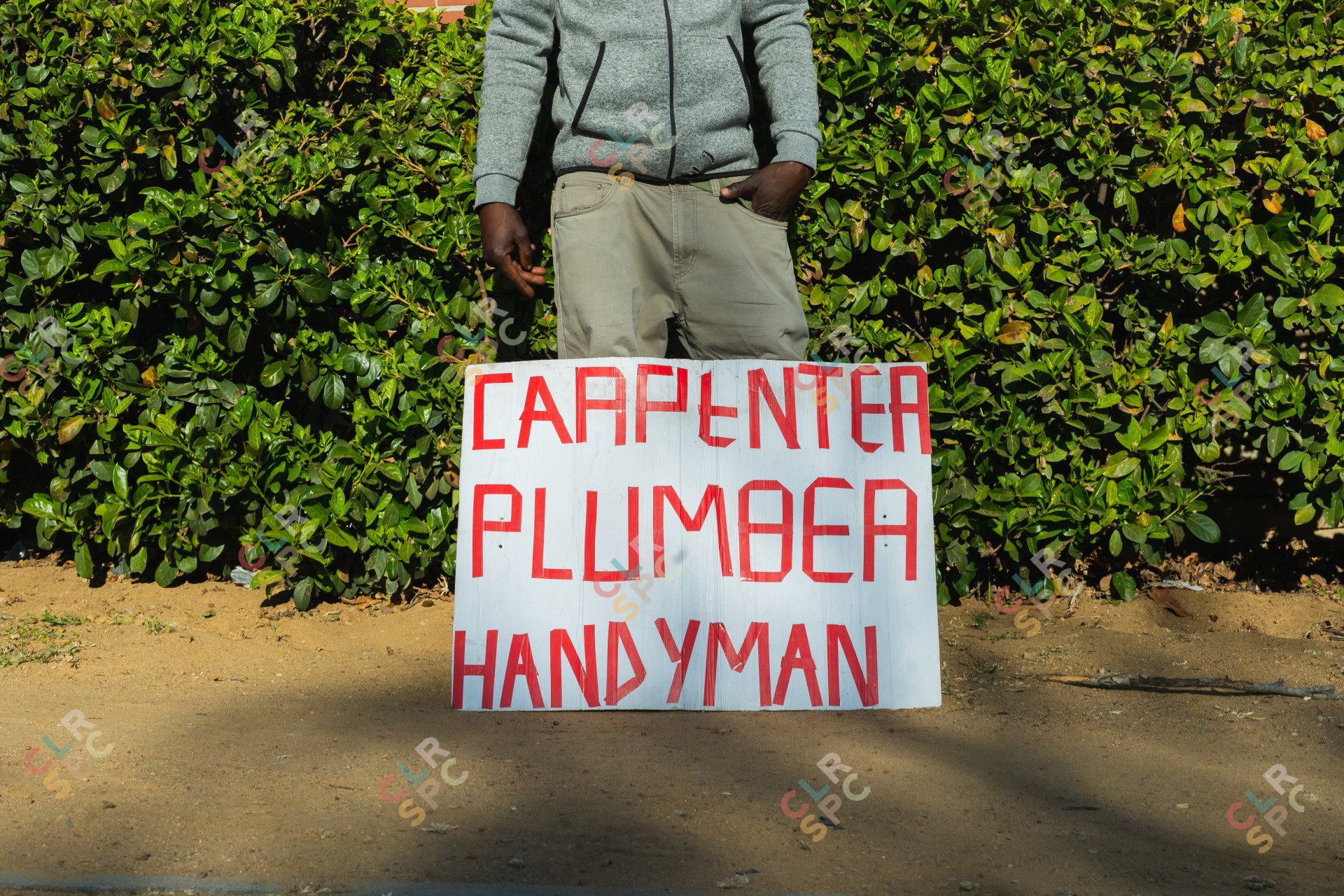 Jobless man with carpenter, plumber and handyman sign.