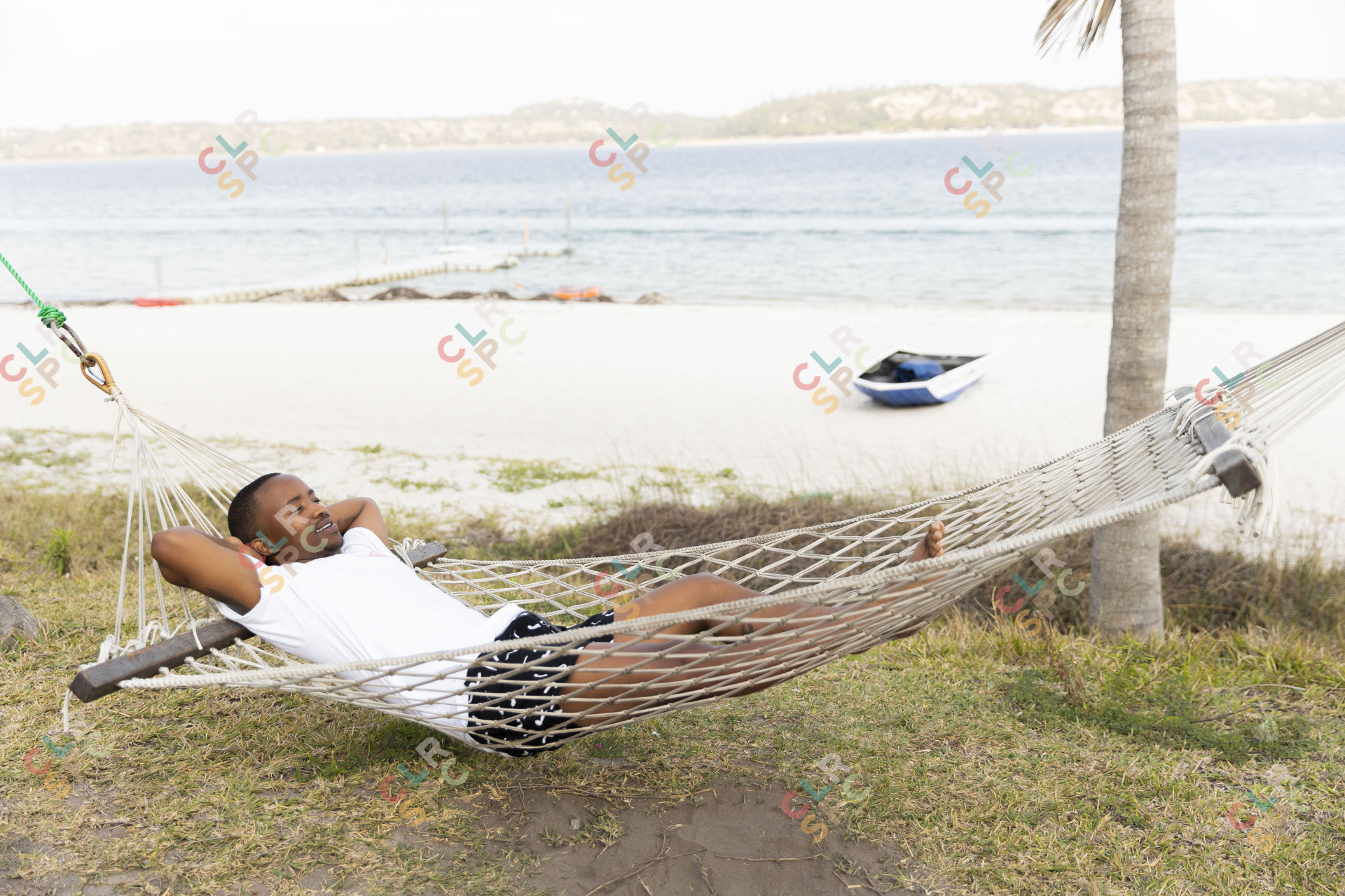 Black man laying on a hammock with a lagoon view.
