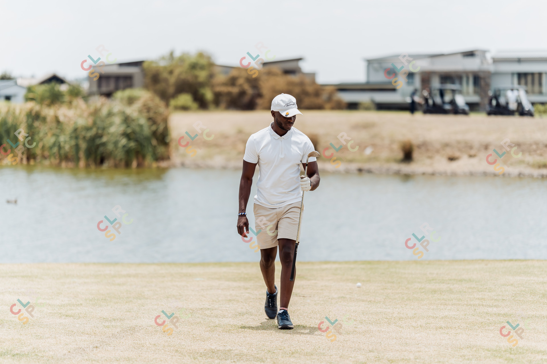 Black male golfer walking with a golf club in hand