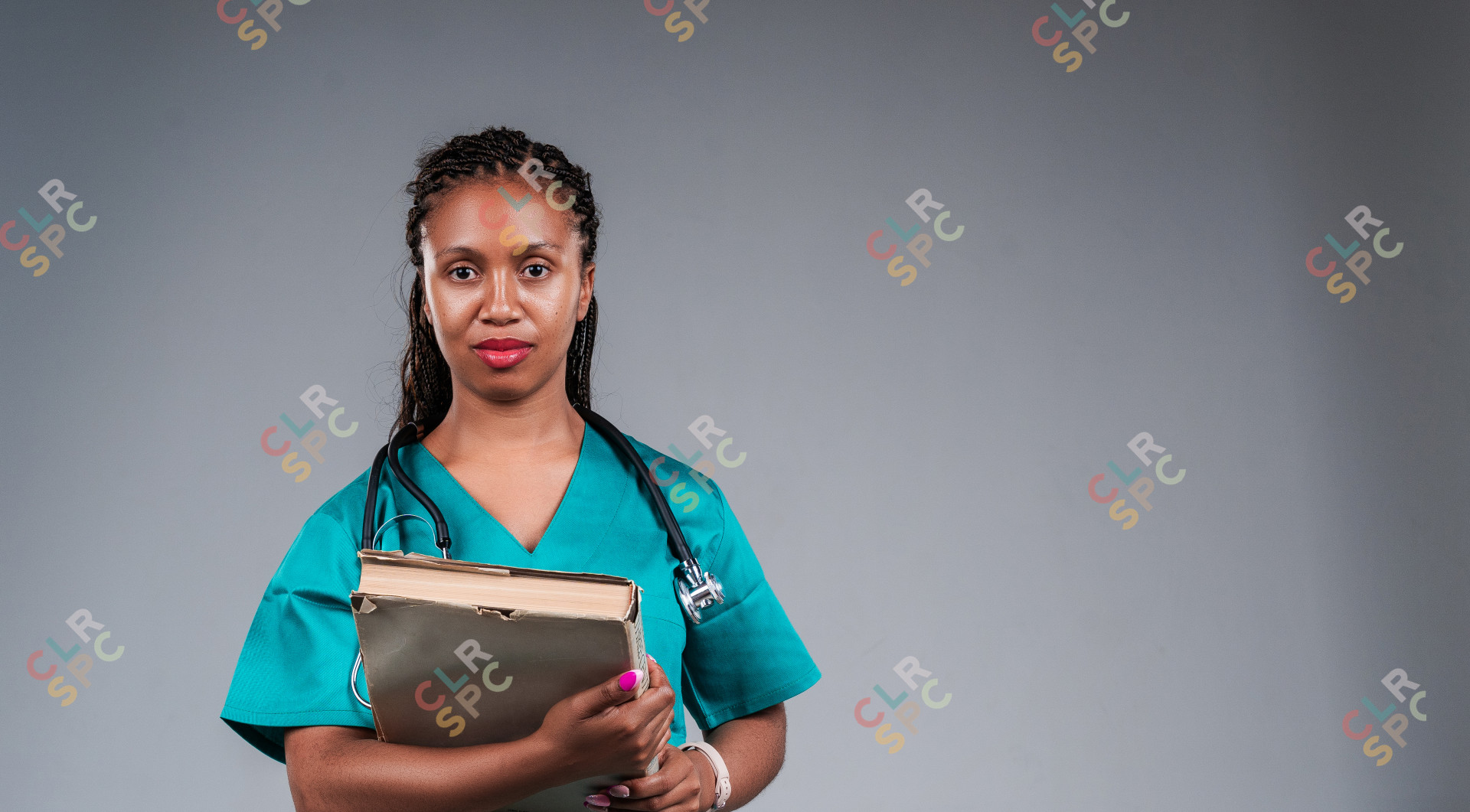 Portrait of young doctor holding books in studio.
