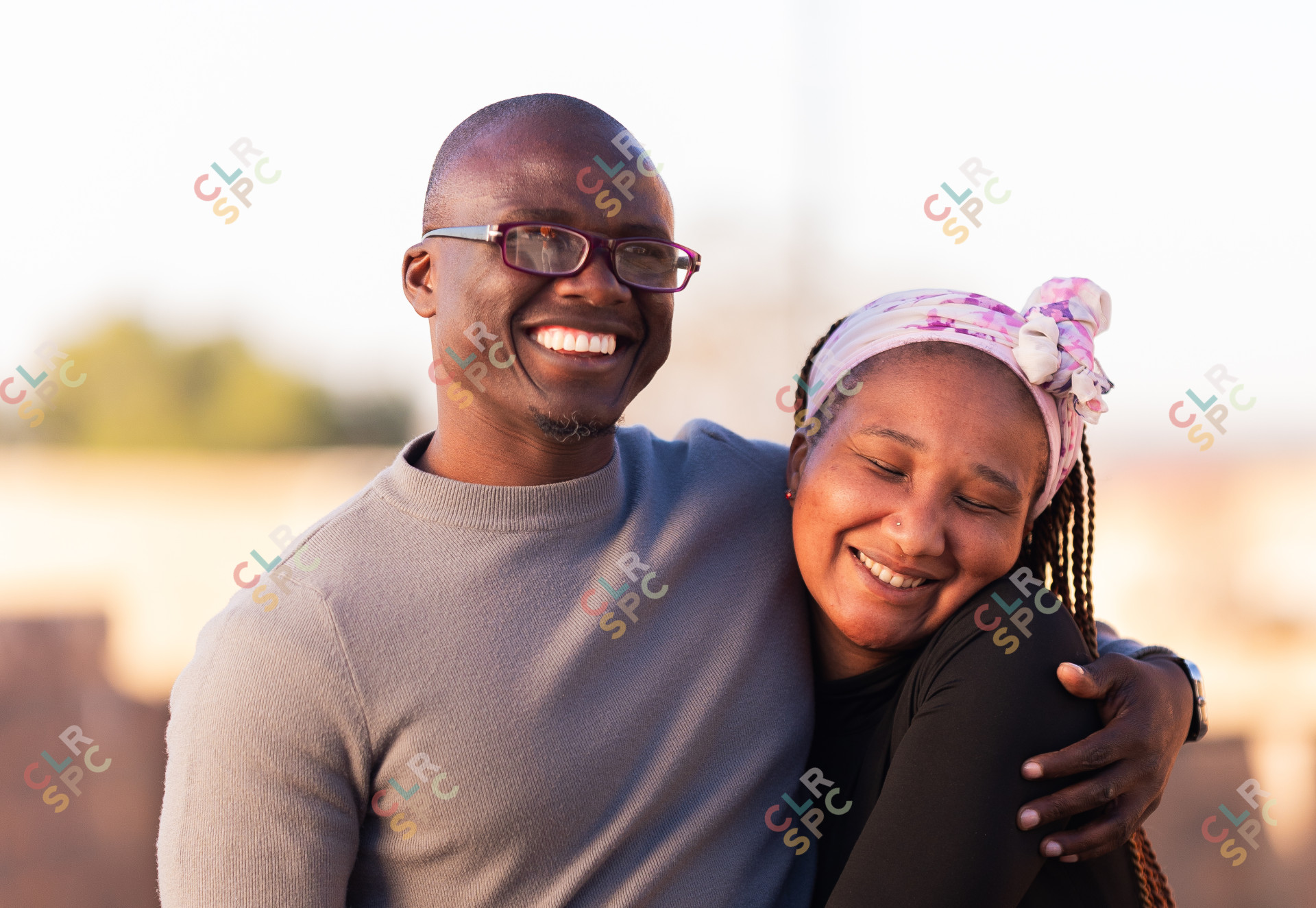Couple smiling outside with woman holding tightly to the man, happy, outside, summer.