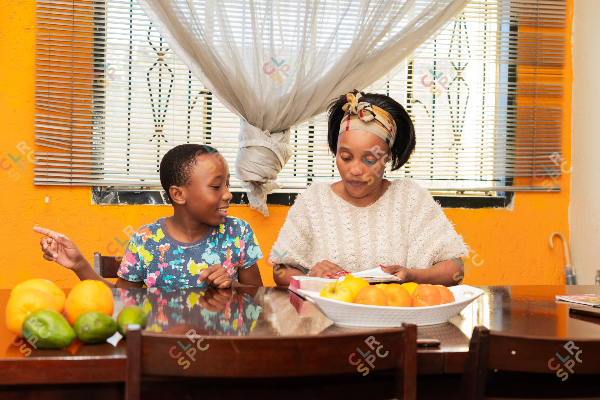 Family reading the bible at home, mom and son with fruits on the table.