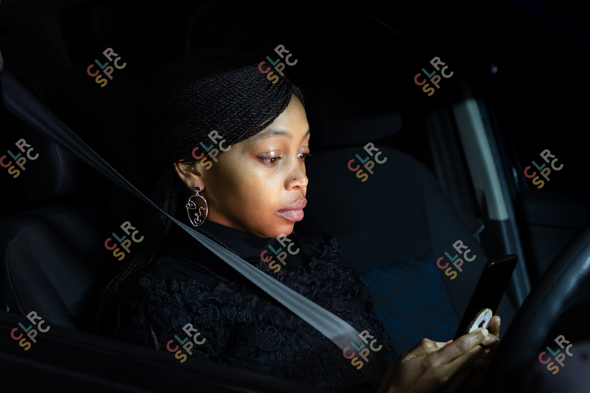 African lady sitting in the car at night chatting on mobile phone.