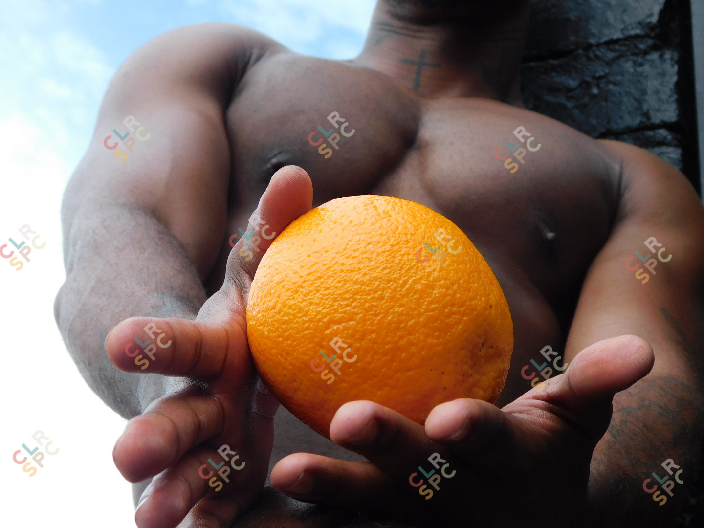A black man holding an orange