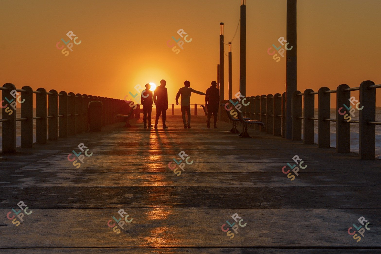 Friends having a morning laugh at the beach while walking towards sunrise direction