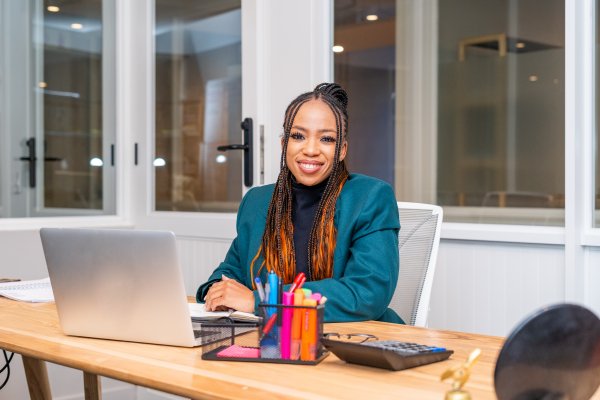 Smiling African black woman sitting at desk looking at the camera.